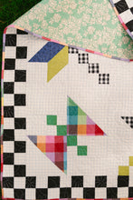Load image into Gallery viewer, Colorful quilt with geometric pattern on a checkered border. Dragonfly Lake Quilt in Picnic Wovens by Suzy Quits for Art Gallery Fabrics. Available at globalfibershop.com