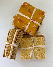 Load image into Gallery viewer, Stack of yellow fabric bundles with floral patterns on a white background