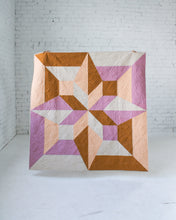 Load image into Gallery viewer, Geometric quilt with pink, brown, and beige colors on a white brick wall background. Arete Quilt bundle by Eudaimonia Studio available at globalfibershop.com.