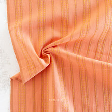 Load image into Gallery viewer, Close-up of orange fabric with yellow stripes. Embrace the charm of the rainbow with Fableism Supply Co’s ‘Lucky Loom’ fabric collection—a dazzling fusion of mixed weight wovens inspired by moments of serendipity. This collection’s palette radiates warmth and whimsy, featuring golden yellows, soft pinks, earthy greens, tranquil blues, and rich purples, each reminiscent of the colors in a lucky rainbow. Available at globalfibershop.com.