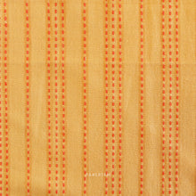 Load image into Gallery viewer, Woven fabric with orange vertical stripes on a yellow background. Embrace the charm of the rainbow with Fableism Supply Co’s ‘Lucky Loom’ fabric collection—a dazzling fusion of mixed weight wovens inspired by moments of serendipity. This collection’s palette radiates warmth and whimsy, featuring golden yellows, soft pinks, earthy greens, tranquil blues, and rich purples, each reminiscent of the colors in a lucky rainbow. Available at globalfibershop.com.