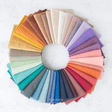 Load image into Gallery viewer, Color swatch wheel with various fabric colors arranged in a circular pattern on a textured white surface. Watercolor Wovens by Fableism Supply co. available at globalfibershop.com.