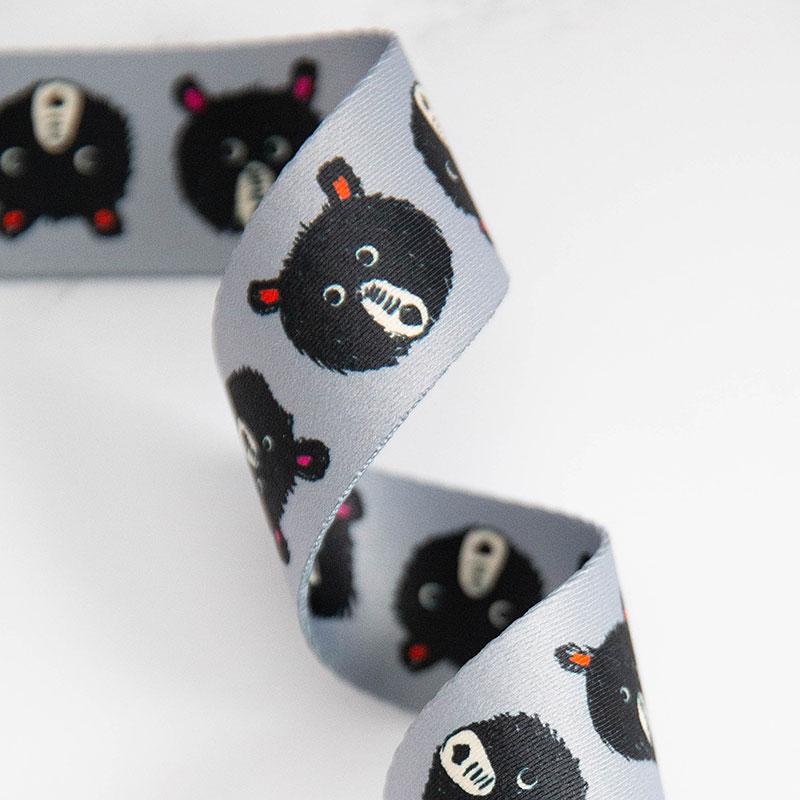 Close-up of ribbon with black animal print on a gray background. Bags, totes, key rings - the possibilities are endless! We are now stocking fun and flirty webbing, designed by your favorite Ruby Star Society designers for Stitch Supply Co. Available at globalfibershop.com.