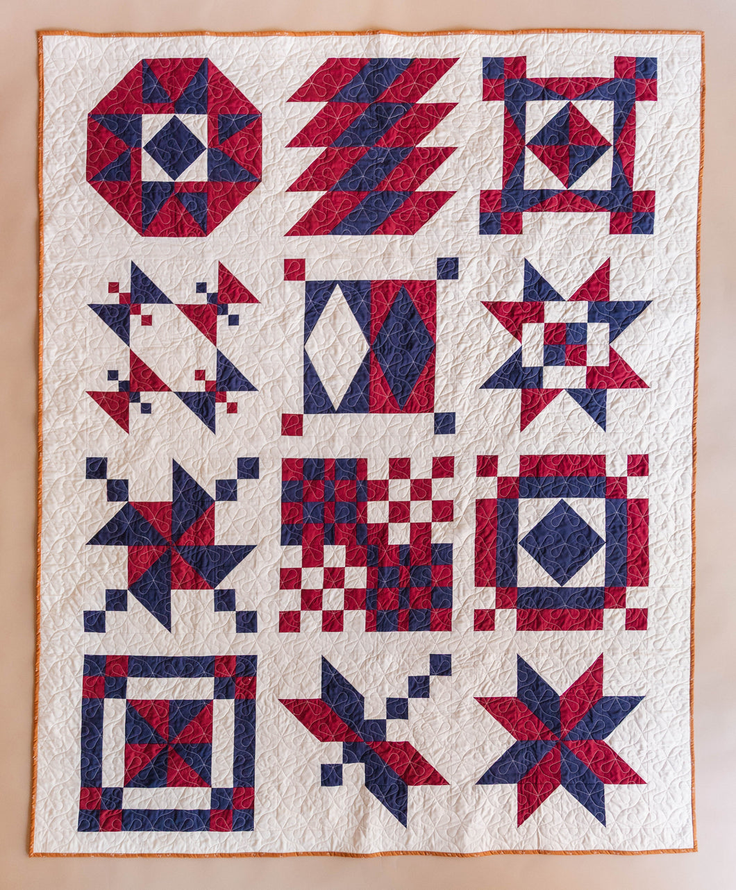 Quilt with red and blue geometric patterns on a beige background