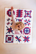Load image into Gallery viewer, Child playing on a colorful quilt with geometric patterns

