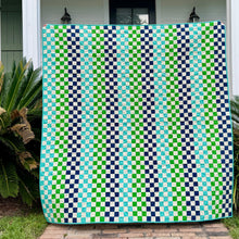 Load image into Gallery viewer, Green and blue patterned quilt draped over a washing machine outside a house.
