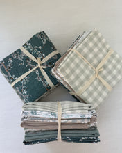 Load image into Gallery viewer, Stacks of folded fabric bundles tied with twine on a white background

