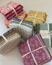 Load image into Gallery viewer, Collection of folded fabric swatches in various colors and patterns on a white surface.
