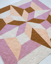 Load image into Gallery viewer, Geometric quilt with pink, brown, and beige colors on a white brick wall background. Arete Quilt bundle by Eudaimonia Studio available at globalfibershop.com.
