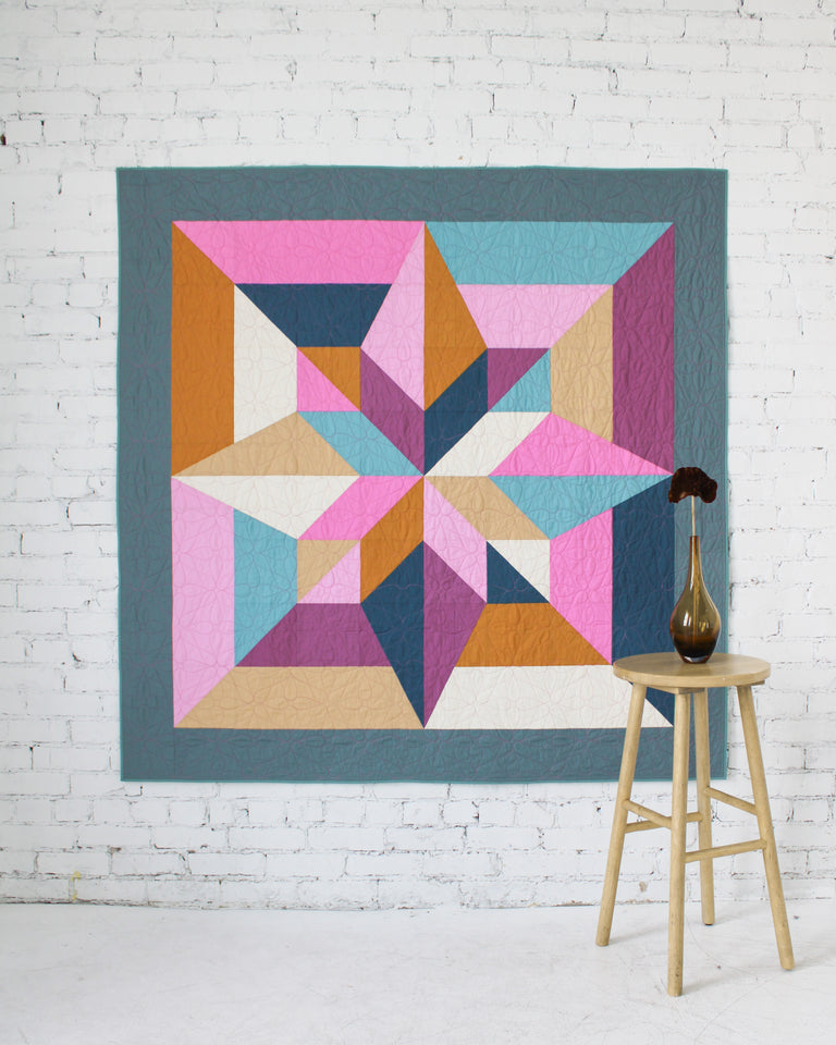 Colorful geometric quilt with star pattern on a white background. Arete Quilt bundle in Jewel by Eudaimonia Studio, available at globalfibershop.com.