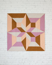 Load image into Gallery viewer, Geometric quilt with pink, brown, and beige colors on a white brick wall background. Arete Quilt bundle by Eudaimonia Studio available at globalfibershop.com.
