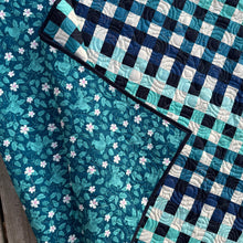 Load image into Gallery viewer, Quilt with blue and white checkered pattern transitioning to floral design
