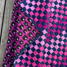 Load image into Gallery viewer, Quilt with pink and purple checkered pattern on a wooden surface

