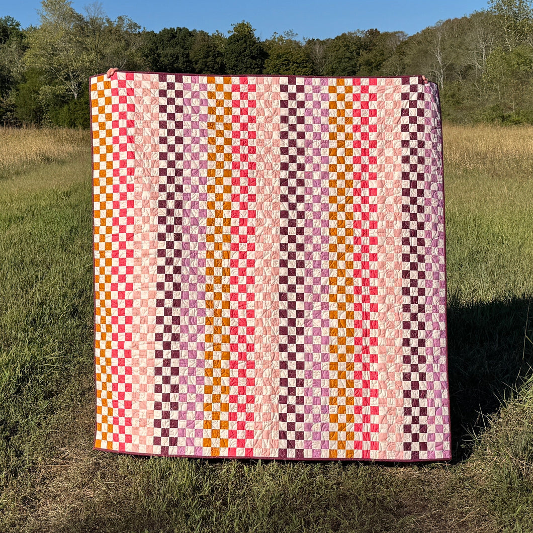Colorful quilt with geometric pattern in a grassy field