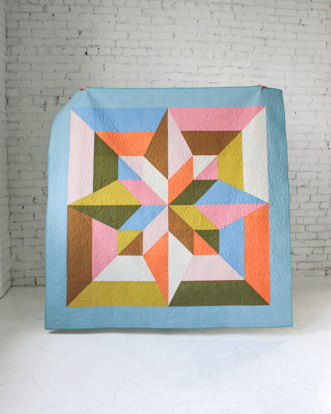 Colorful geometric quilt with star pattern on a white background. Arete Quilt bundle in Jewel by Eudaimonia Studio, available at globalfibershop.com.