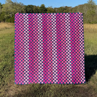 Pink and purple checkered pattern in a grassy field