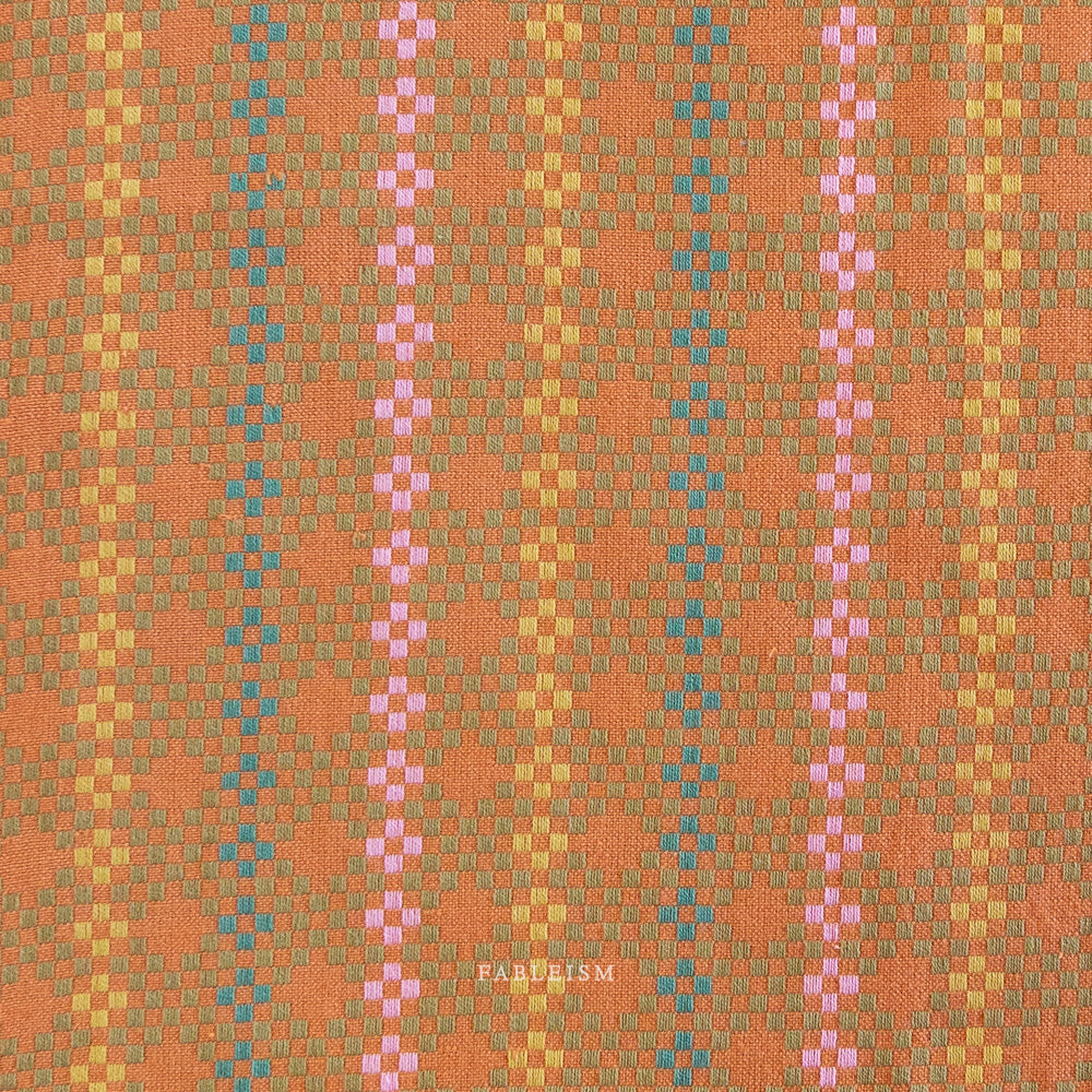 Woven fabric with a geometric design featuring shades of orange, pink, and green. Embrace the charm of the rainbow with Fableism Supply Co’s ‘Lucky Loom’ fabric collection—a dazzling fusion of mixed weight wovens inspired by moments of serendipity. This collection’s palette radiates warmth and whimsy, featuring golden yellows, soft pinks, earthy greens, tranquil blues, and rich purples, each reminiscent of the colors in a lucky rainbow. Available at globalfibershop.com.
