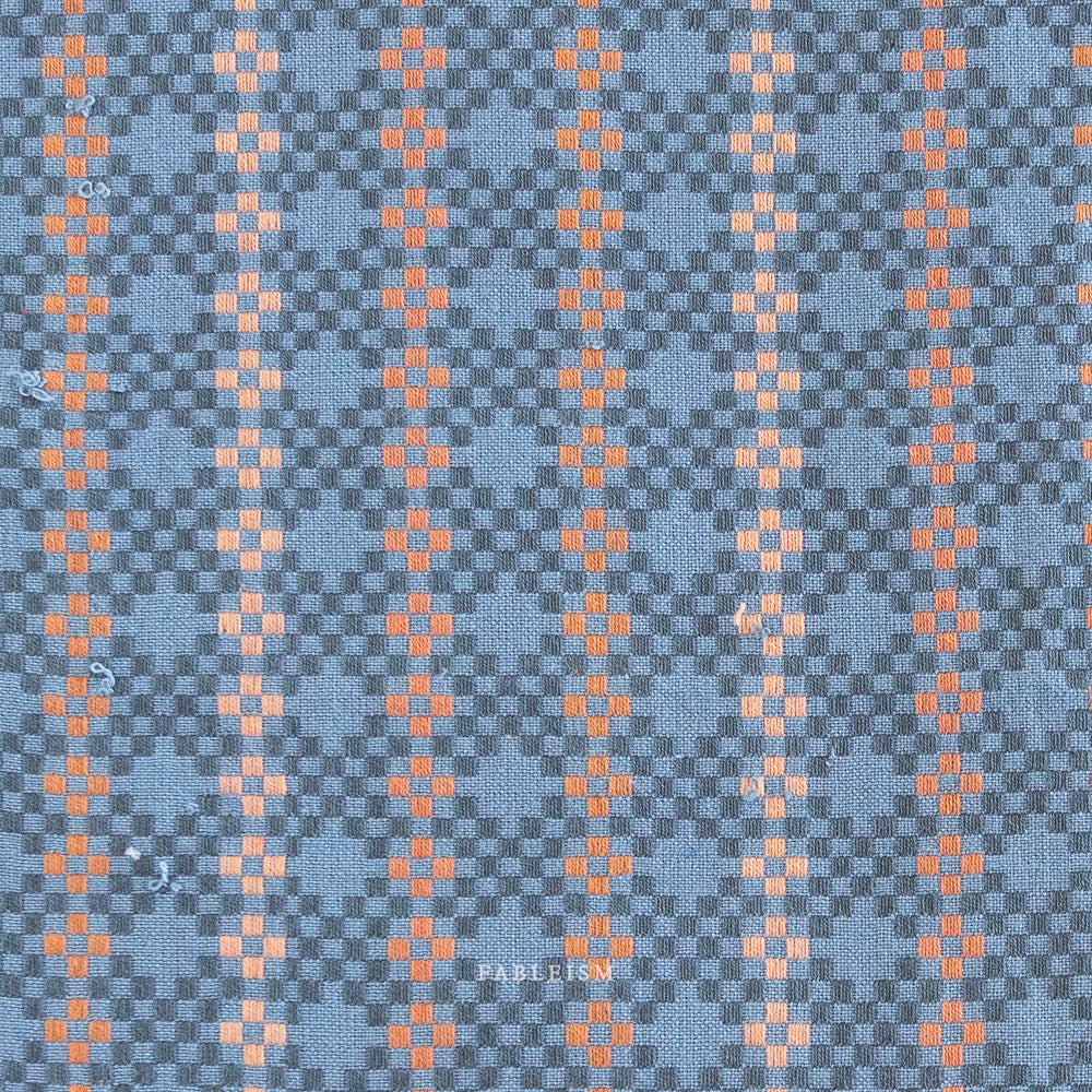 Woven fabric with a blue and orange pattern. Blue and orange woven fabric.  Embrace the charm of the rainbow with Fableism Supply Co’s ‘Lucky Loom’ fabric collection—a dazzling fusion of mixed weight wovens inspired by moments of serendipity. This collection’s palette radiates warmth and whimsy, featuring golden yellows, soft pinks, earthy greens, tranquil blues, and rich purples, each reminiscent of the colors in a lucky rainbow. Available at globalfibershop.com.