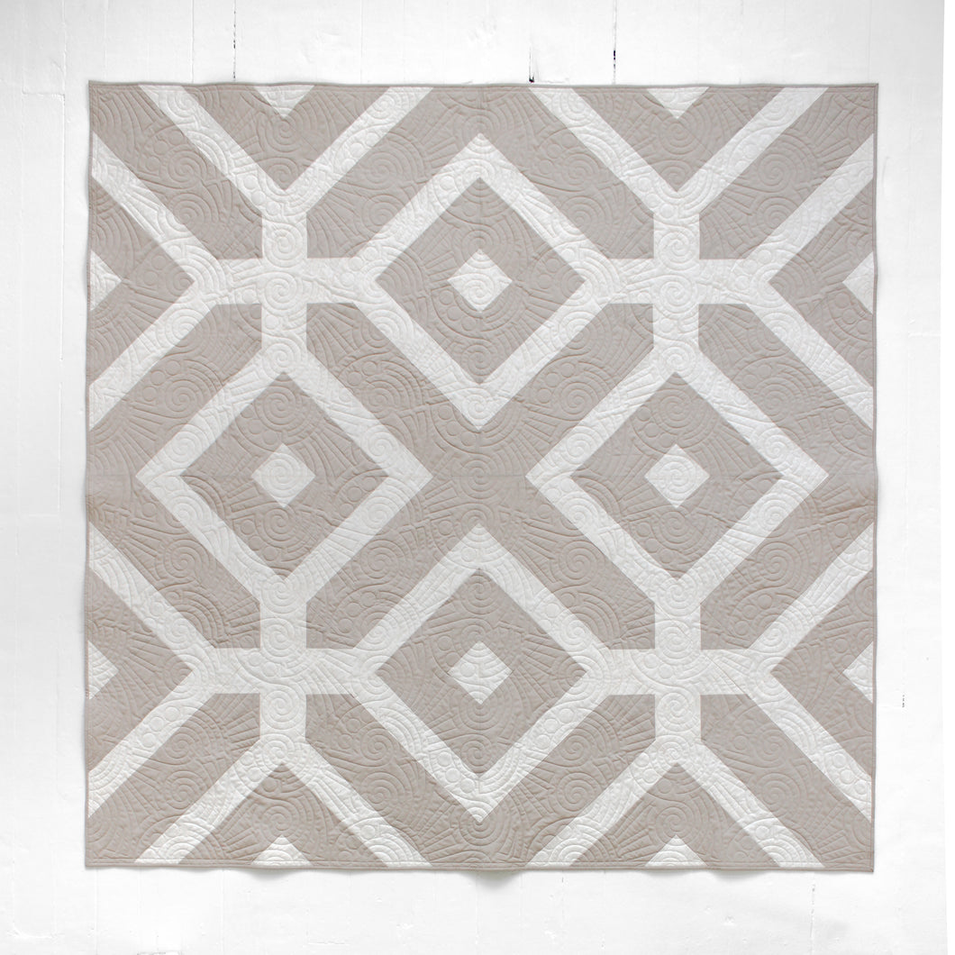 The Villager Quilt design reflects how “villagers” link arms and surround their community members in times of need.  The two-tone Winter White version is available at globalfibershop.com.