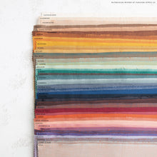 Load image into Gallery viewer, Color swatch wheel with various fabric colors arranged in a circular pattern on a textured white surface. Watercolor Wovens by Fableism Supply co. available at globalfibershop.com.

