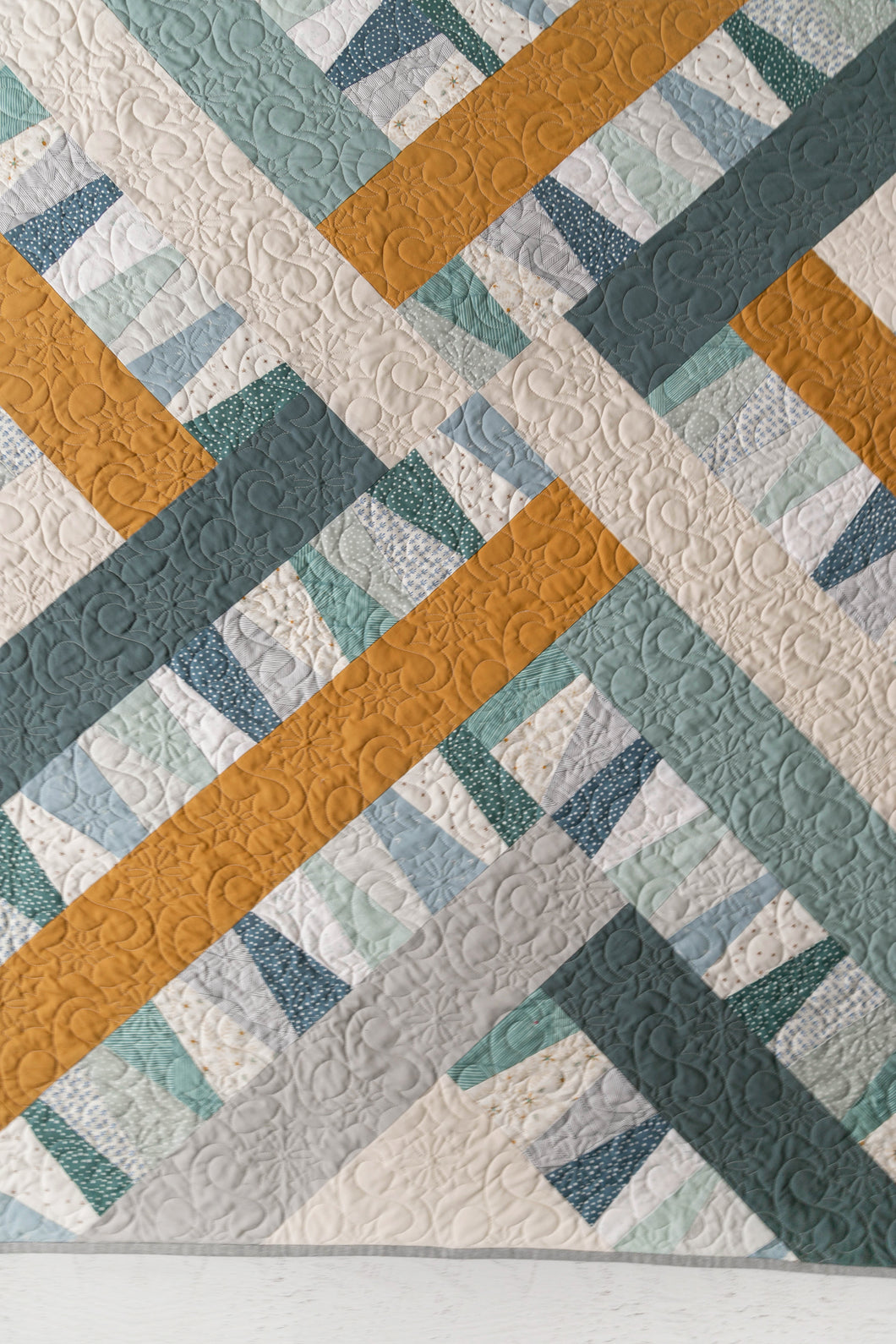 Garland quilt pattern by Suzy Quilts in Winter Walk colorway of light blue, teal and gold.  Quilt kits available at globalfibershop.com.